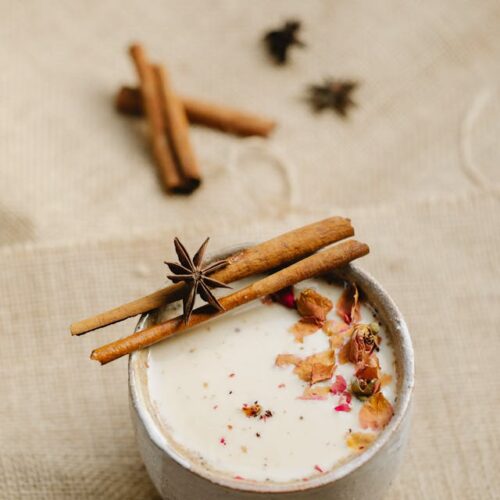 A cup of spiced chai tea with a cannabis twist, garnished with a cinnamon stick.