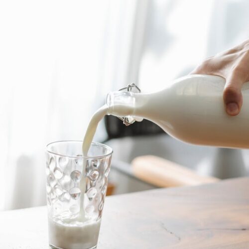 A jug of milk pouring into a glass, illustrating the preparation of cannabis-infused milk.