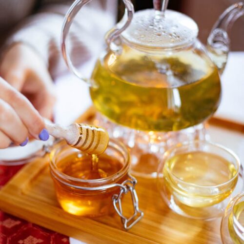 A jar of honey being stirred on a tray, demonstrating the process of making cannabis-infused honey.